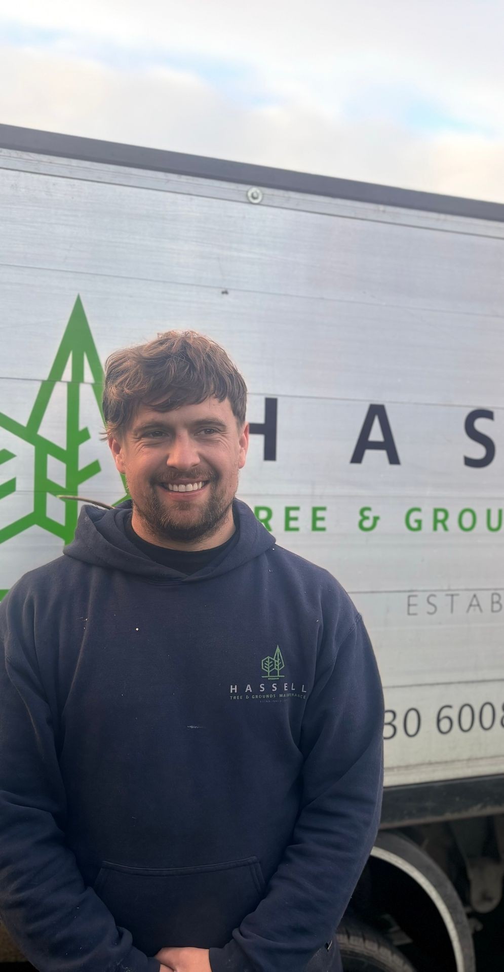 Man smiling in front of a truck with a logo and text on the side.